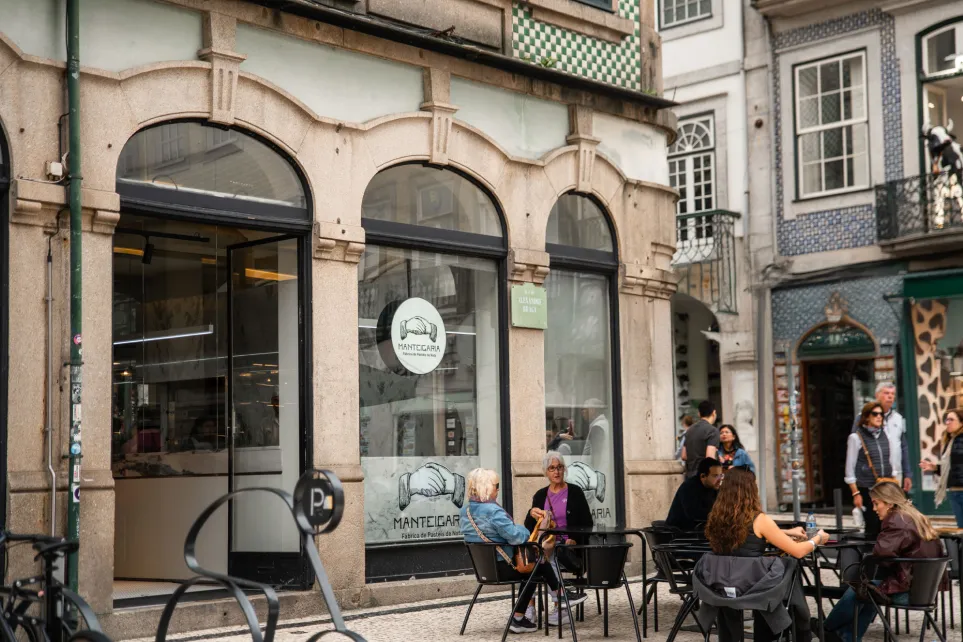 Fachada da Manteigaria no Porto, com esplanada e pessoas sentadas