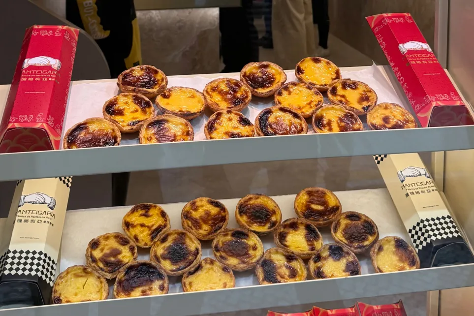 Pasteles de nata dispuestos en bandejas en el escaparate, junto a envases rojos