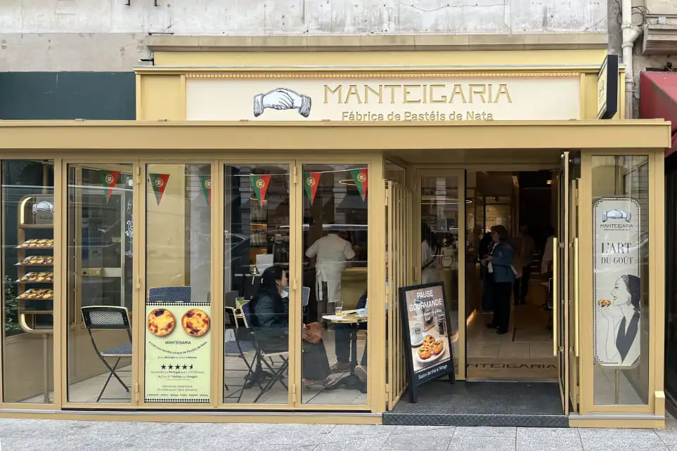 Vitrine da Manteigaria em Paris com cartaz Pause Gourmande e pastéis de nata em exposição
