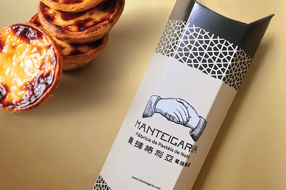Pastéis de nata ao lado de uma embalagem docesecafe.live o nome da marca em caracteres chineses