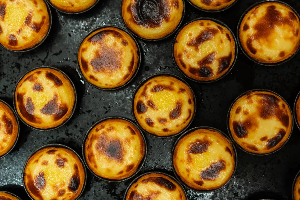 Fornada de pastéis de nata acabados de sair do forno, vistos de cima