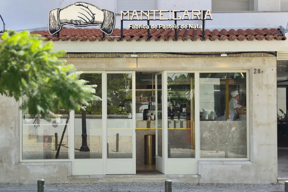Fachada da Manteigaria em Cascais, com o logótipo das mãos sobre telhado de telha