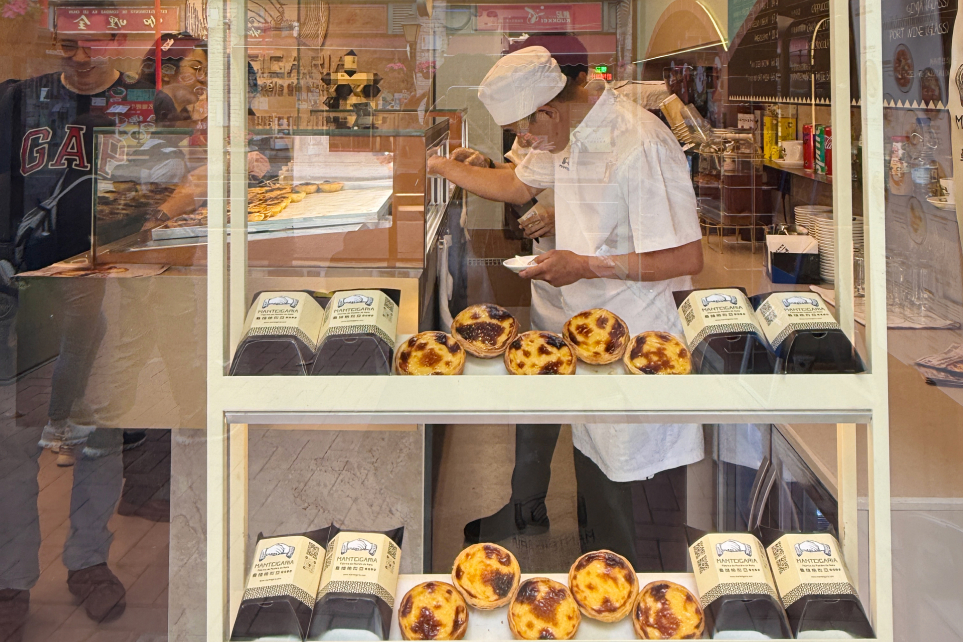 Padeiro da Manteigaria a preparar pastéis de nata na montra de uma loja em Hong Kong