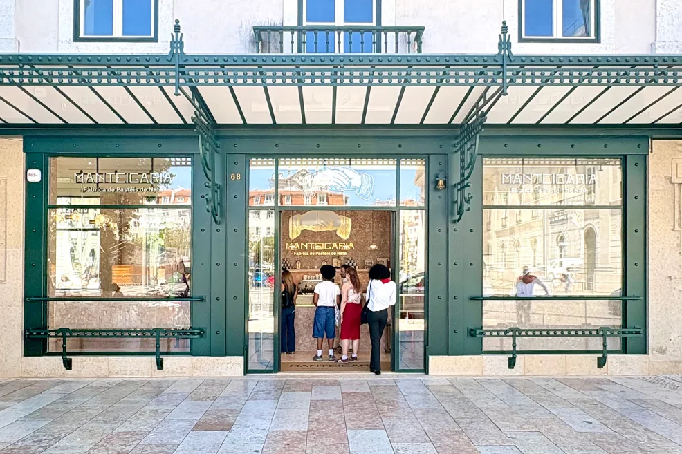 Fachada verde da Manteigaria no Rossio, com toldo e clientes a fazer fila