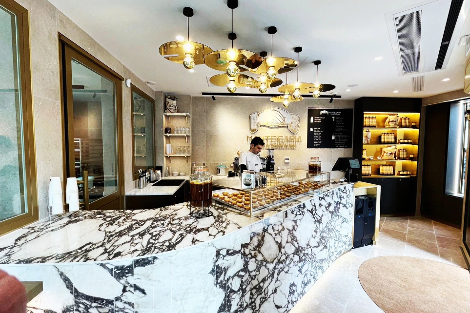 Baker working behind the Manteigaria marble counter, with pastries on display