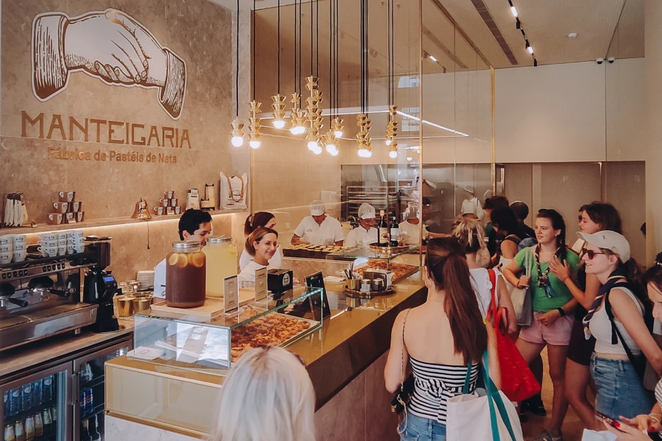 Interior movimentado da docesecafe.live balcão dourado e clientes a fazer fila