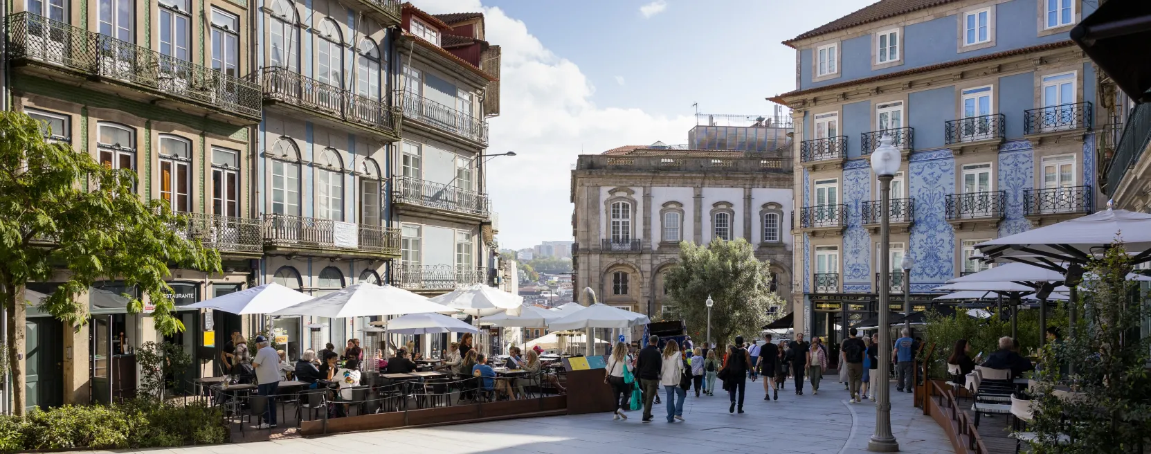 Calle con terrazas y azulejos portugueses, en una plaza concurrida con gente paseando